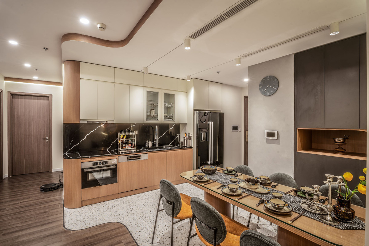 Khu vực bếp được gia chủ đầu tư và dành diện tích rộng rãi. Tủ bếp màu trắng và màu gỗ được thiết kế bo tròn ở góc, trang bị bếp từ và đầy đủ các vật dụng tiện nghi, tổng thể gọn gàng và ngăn nắp.