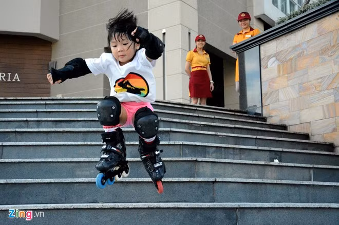 T ại khu chung cư các học viên đang được luyện tập môn thể thao này, có nhiều địa hình phù hợp được anh Thịnh lựa chọn và hướng dẫn các học viên của mình luyện tập như bậc thang, hành lang, bục ghế ngồi, những chỗ có độ dốc... để tập luyện những động tác từ cơ bản đến khó của patin. Trong ảnh: Bé Lỳ tự tin thực hiện một động tác ở cấp độ khó hơn khi nhảy từ bậc thứ 4 của bậc thang lên xuống chung cư khiến nhiều người lớn thán phục khi xem.