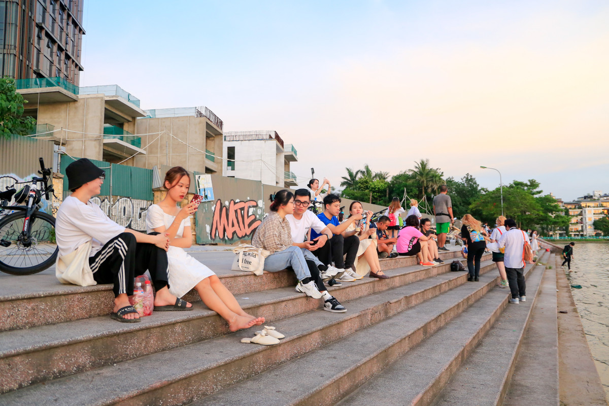 Cách "cây cô đơn" không xa, nhiều bạn trẻ chọn các bậc cầu thang dẫn xuống hồ Tây làm nơi dừng chân và ăn uống, tán gẫu, ngắm hoàng hôn.