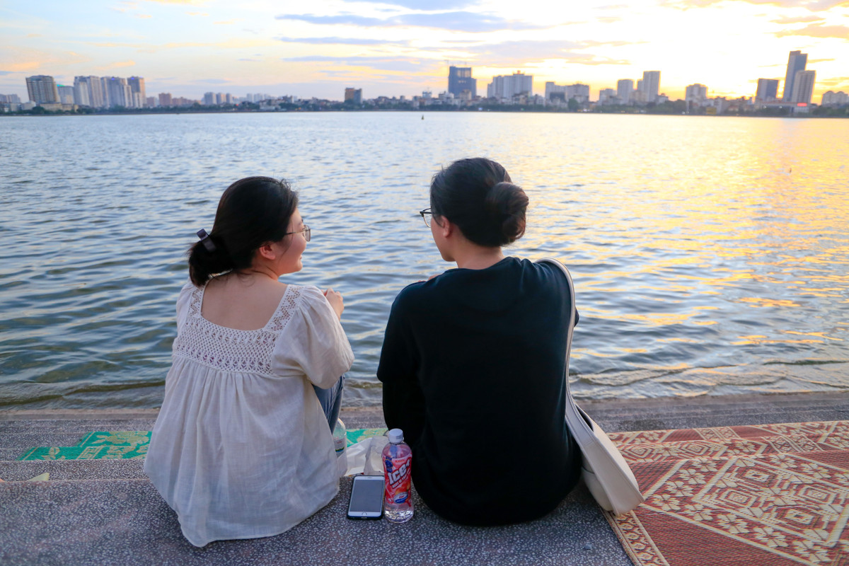 Nhung và Mai (sinh năm 1999) mua thêm nước uống, đồ ăn vặt trong lúc ngồi ở mạn hồ. "Thời tiết không khiến bọn mình khó chịu lắm bởi trời nắng to mới dễ có hoàng hôn đẹp, cũng không sợ tốn xăng vì lâu rồi mới đi lượn. Nay bọn mình nổi hứng lên hồ Tây, cảm giác giống như ôn lại thời sinh viên khi có nhiều thời gian rảnh, còn giờ hai đứa đều đã đi làm, 2-3 tháng mới ghé qua đây lúc cuối chiều", Mai chia sẻ.