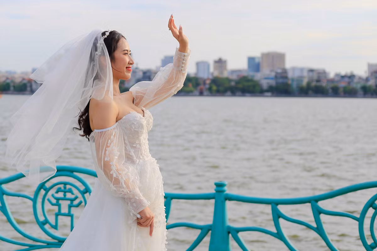 "Mình chọn hồ Tây làm nơi ghi hình ảnh cưới bởi không gian thoáng đãng, ánh sáng tự nhiên với cảnh sóng nước đằng sau. Ban đầu, mình dự định chụp cả ở 'cây cô đơn' nhưng rất tiếc cây đã bị đốn hạ. Khi mới yêu nhau, hai vợ chồng cũng thỉnh thoảng lấy nơi này làm chỗ hẹn hò", Mai (27 tuổi) cho biết. Chụp ngoài trời vào ngày nắng nóng 37 độ C, cô dâu có chút mệt nhưng hy vọng săn được cảnh đẹp vào cuối chiều.