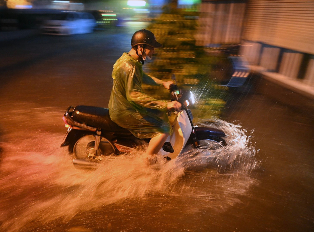 Tại một ngõ trên đường Trường Chinh (quận Đống Đa) lúc 20h30, nhiều người đi xe máy cố gắng băng qua đoạn ngập. Ảnh: Việt Linh.