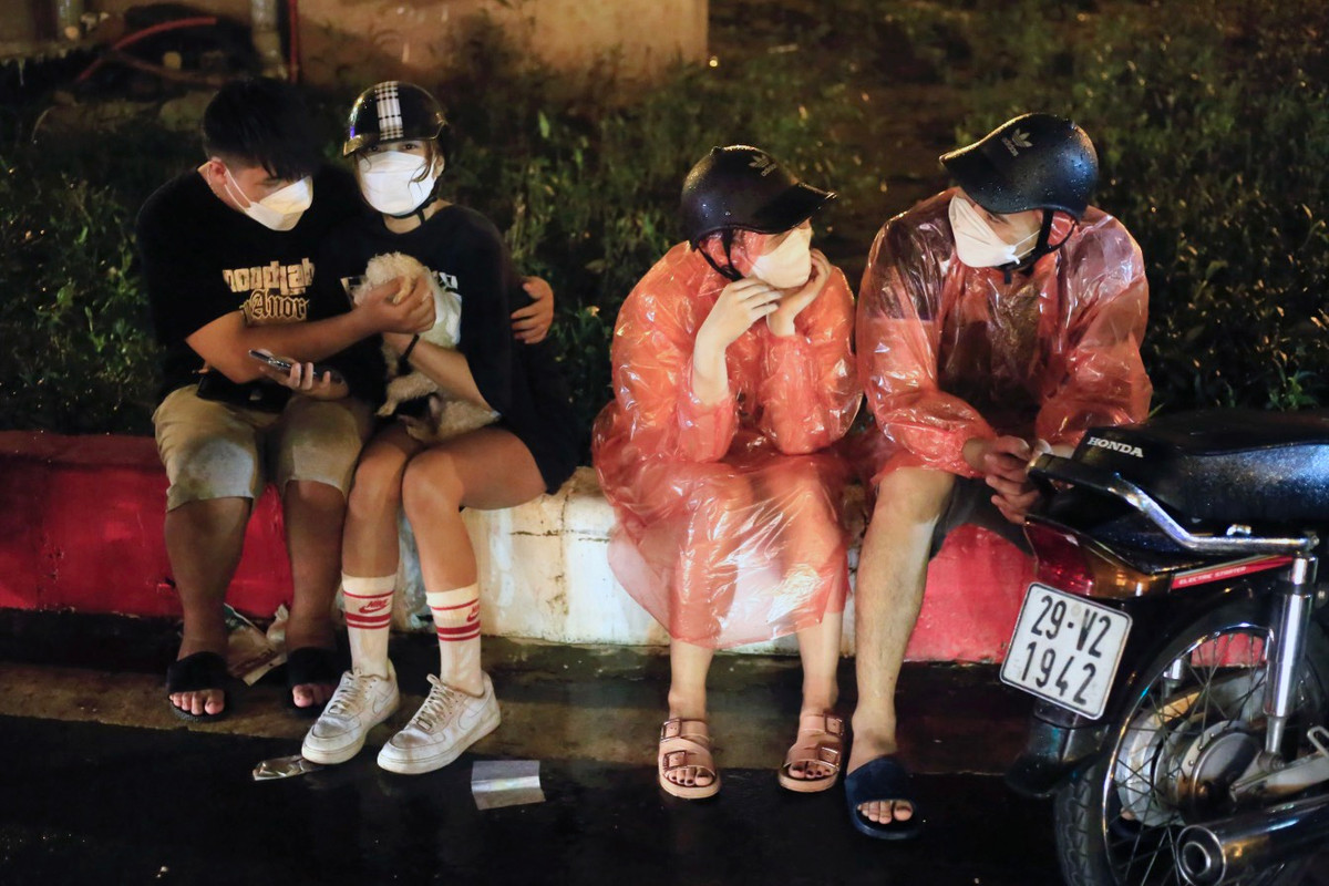 Anh Tùng (ngoài cùng bên phải) đi từ đường Láng sang phía gần cầu Mễ Trì thì gặp mưa lớn, phải đợi đến lúc ngớt mới dám di chuyển tiếp. Ảnh: Tuấn Anh.