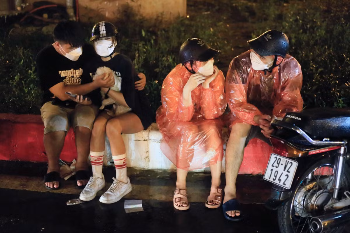 Anh Tùng (ngoài cùng bên phải) đi từ đường Láng sang phía gần cầu Mễ Trì thì gặp mưa lớn, phải đợi đến lúc ngớt mới dám di chuyển tiếp. Ảnh: Tuấn Anh.