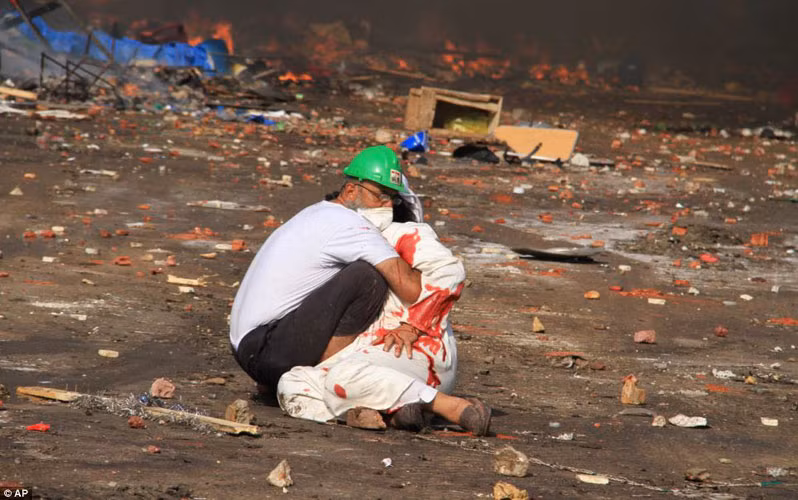 Người đàn ông ôm chặt một người biểu tình bị thương nặng, máu nhuộm đỏ chiếc áo dài trắng trong cuộc đụng độ với quân đội chính phủ hôm qua ở quận Nasr City, phía Đông Cairo.