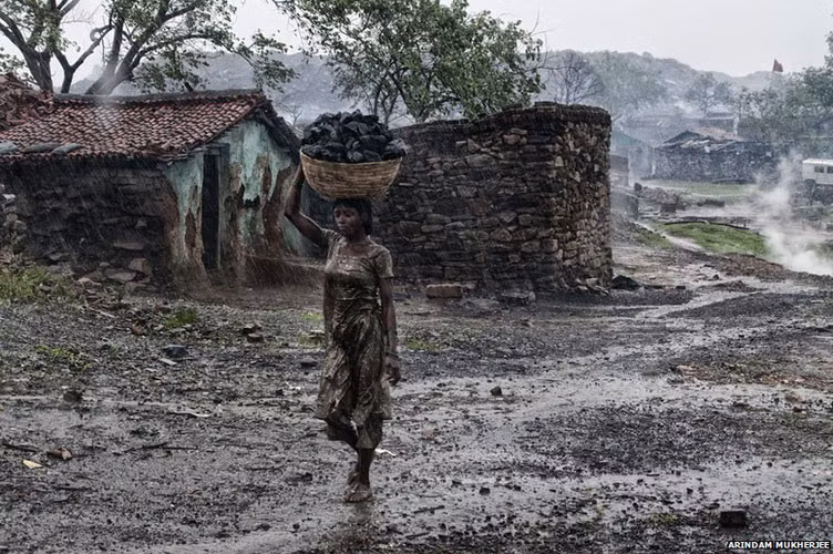 Nhiều thợ mỏ và các thành viên gia đình họ liều mạng xâm nhập vào các mỏ than đang cháy để khai thác than bán lấy tiền. Trong ảnh, một cô gái đội rổ than đầy từ một mỏ lộ thiên.