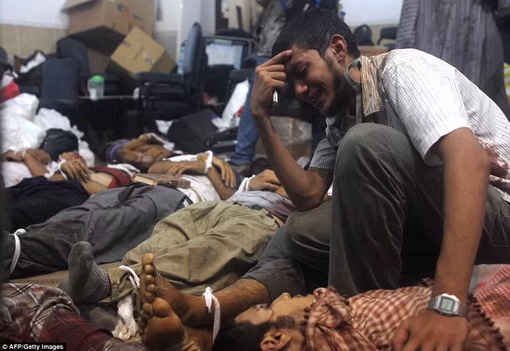 Một người đàn ông khóc lóc thảm thiết giữa thi thể của hàng trăm người sau các vụ đụng độ đẫm máu với quân đội chính phủ hôm qua.