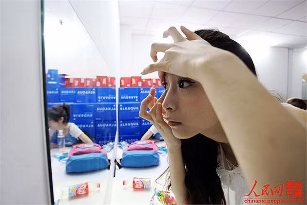Hậu trường là cảnh tượng bận rộn, mọi người vội vàng trang điểm cho mình. Trương Diệp Giai bình tĩnh hơn, vì cô đã chuẩn bị khá kỹ trước đó, chỉ cần chỉnh sửa một chút và thay trang phục là có thể đi ra. Cô đang gắn kính áp tròng để có một đôi mắt to