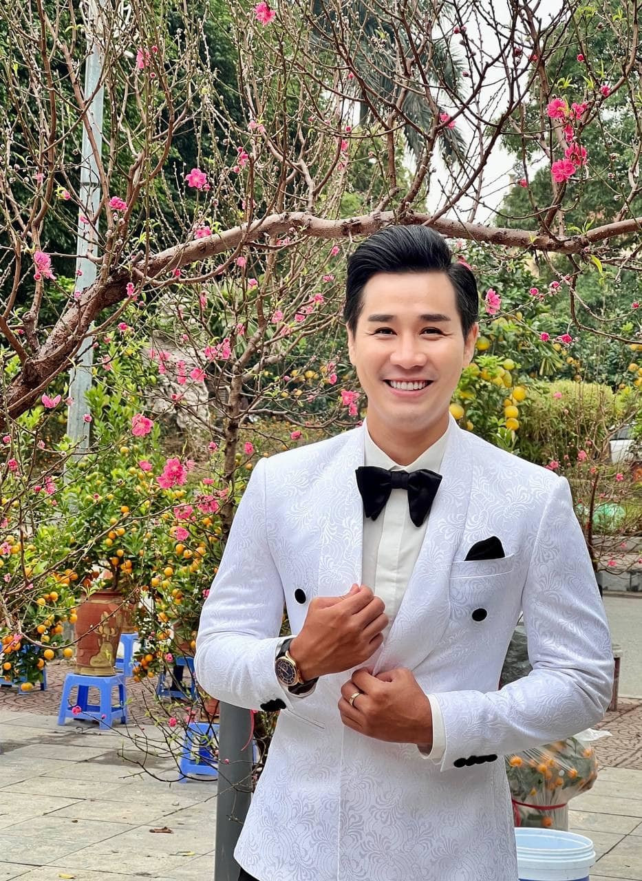 MC Nguyên Khang đăng ảnh bên hoa đào rực rỡ.