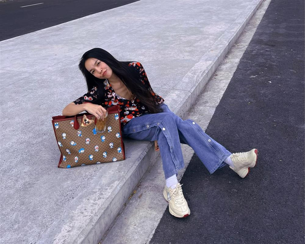 ẫn là họa tiết Doraemon trên túi nhưng khi ngồi bệt uống cafe trên phố, cô không ngại phanh cúc áo trễ sâu để lộ toàn bộ thềm ngực.