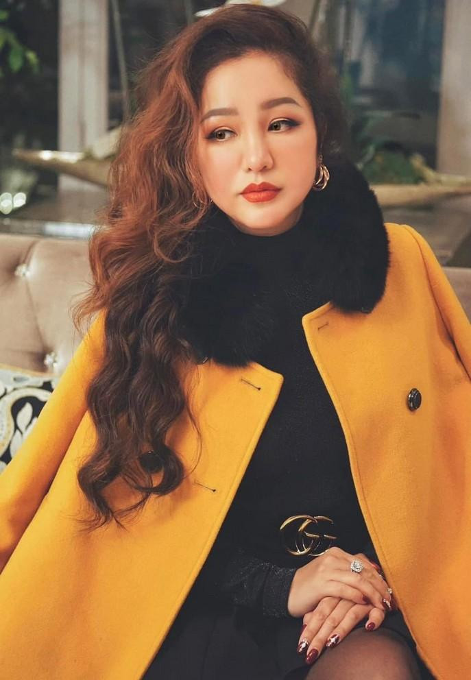 Nghệ sĩ Thúy Nga diện áo khoác, khăn choàng dày chụp ảnh mùa đông giữa ngày hè oi bức.