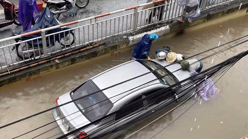 Một số người dân đang cố gắng giải cứu chiếc xe ô tô chết máy (Ảnh: T.K). 