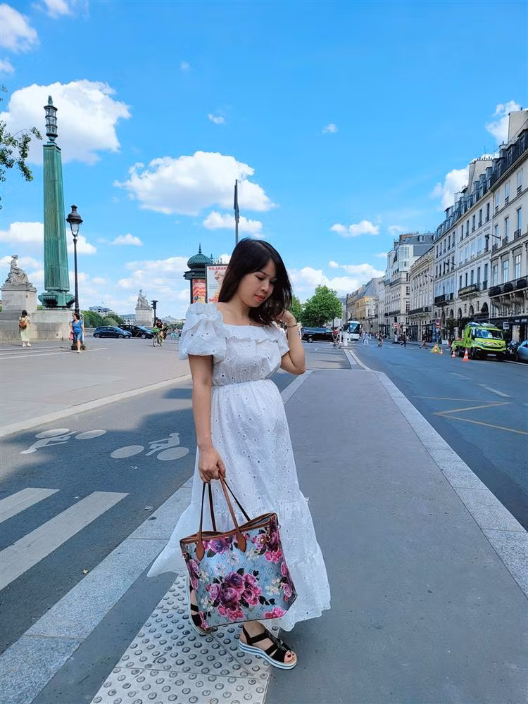 Thiết kế váy trắng ren đục lỗ dáng xòe dài giúp cô "ăn gian" tuổi tác đáng kể. Cả chuyến đi, cô cũng khéo đi sandal đế thấp vừa an toàn cho thai nhi lại dễ dàng di chuyển.