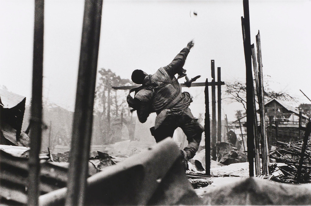 Một binh sĩ Mỹ ném lựu đạn khi đứng giữa một khu dân cư đã bị san phẳng bởi chiến sự.