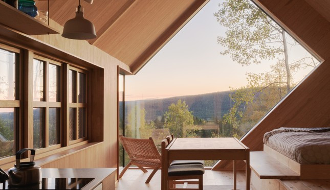 Với phần mặt tiền được thiết kế thú vị và nội thất gỗ ấm cúng, khung cảnh hoàng hôn, rừng cây và hồ nước đẹp siêu thực được chủ nhân ngôi nhà bắt trọn.