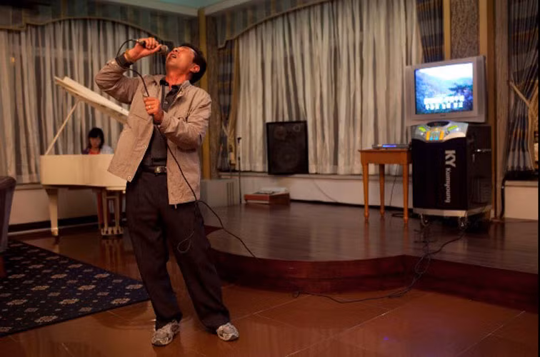 Một nam trung niên hát karaoke trong khi con gái chơi piano tại một quán bar ở khách sạn núi Kumgang .