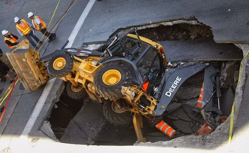 Một chiếc máy xúc nằm lơ lửng trên miệng hố tử thần trên phố Saint-Catherine ở Montreal, Quebec, Canada ngày 5/8/2013.