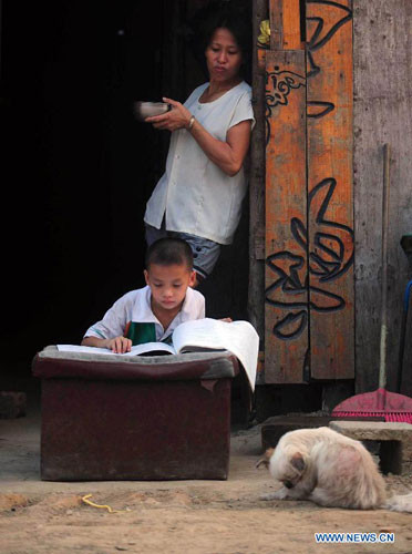Bé trai Yang Peng, 8 tuổi ở làng Donghe, thành phố Baise, chăm chỉ làm bài tập với chiếc bàn học là chiếc đệm rách nát.
