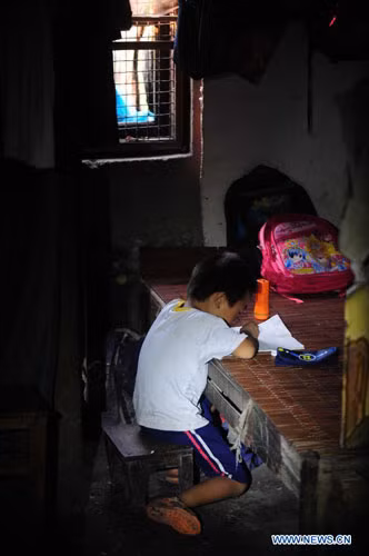 Bé trai Shi Jincheng, 6 tuổi ở làng Baisha thành phố Liuzhou, làm bài tập trên chiếc giường ọp ẹp.