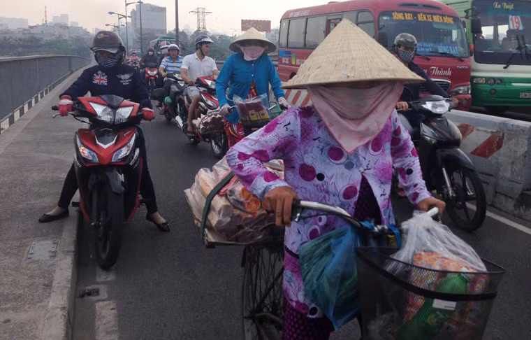 Trong dòng xe tấp nập trên cầu Bình Triệu, quận Bình Thạnh, 2 người phụ nữ khá vất vả đạp xe lên dốc cầu bán dạo nhang.