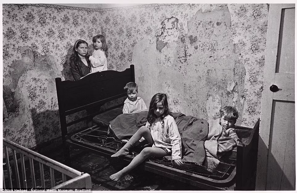 Nhiếp ảnh gia Nick Hedges đã dành 3 năm để chụp ảnh cuộc sống tồi tàn của người dân Anh hơn 40 năm về trước. Người phụ nữ có tên M cùng chồng và 4 con nhỏ ở trong một căn phòng nhếch nhác, tồi tàn ở Balsall Heath, Birmingham. Nơi họ sinh sống không có phòng tắm, nước nóng để sử dụng. Tường nhà ẩm mốc, bong tróc và không có cả một chiếc giường tử tế để ngủ. Ảnh chụp tháng 1/1969.