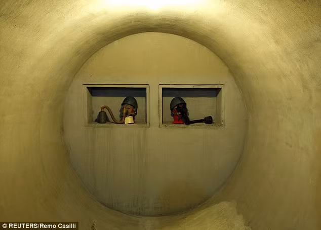 Mặt nạ phòng độc và mũ được chuẩn bị sẵn sàng đặt trong lỗ tròn ở phía cuối hành lang.