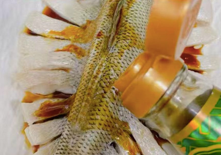  Đổ nước cá hấp ra khỏi nồi, thêm hành lá cắt nhỏ, đặt các khoanh ớt đỏ, rưới dầu nóng và nước tương cá hấp lên trên rồi thưởng thức.