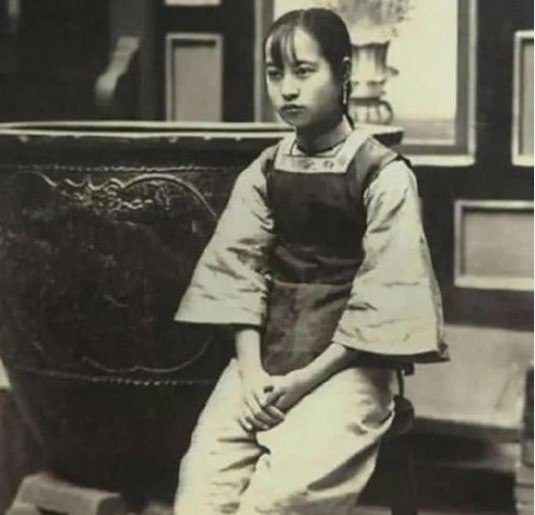 Mặc dù cô gái trong ảnh ăn mặc không lộng lẫy nhưng quần áo tuềnh toàng không che giấu được vẻ đẹp thanh tú. Xét theo trang phục, có lẽ cô là một a hoàn của một gia đình giàu có.