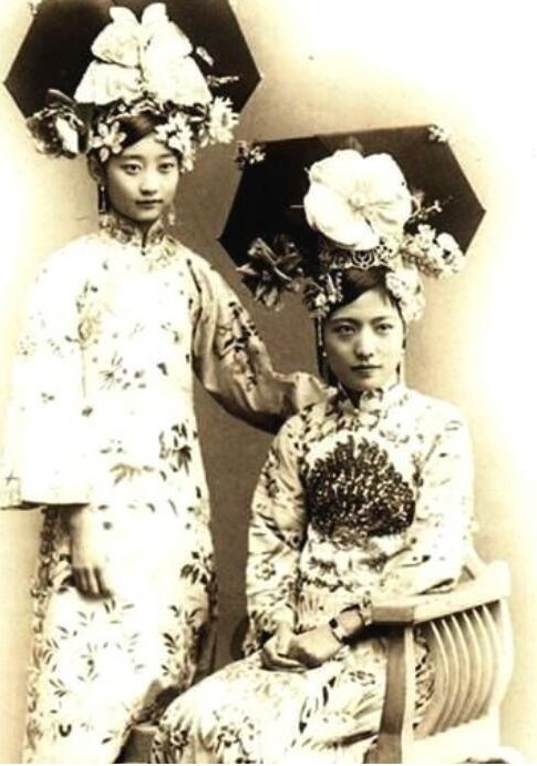 Người đứng bên trái bức ảnh là mỹ nhân nổi tiếng cách cách Vương Mẫn Đồng thời nhà Thanh. Cô là em họ của hoàng hậu Uyển Dung. Lúc 9 tuổi, cô vào cung tham dự hôn lễ và đem lòng yêu hoàng đế Phổ Nghi. Đáng tiếc, bà đã trao trái tim cho một người đàn ông không bao giờ thuộc về mình, dù cố gắng hết sức nhưng vẫn không thể gây ấn tượng với đối phương.