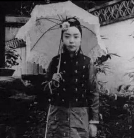 Thời nhà Thanh có rất nhiều nữ nhân quý tộc từ nhỏ đã rất xinh đẹp. Đây là một thiếu nữ cầm ô đứng trong hẻm, qua bức ảnh có thể hình dung rằng khi lớn lên cô ấy chắc chắn sẽ là một mỹ nhân.