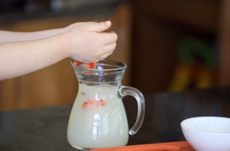 Pha sẵn dung dịch đường với nước cốt chanh rồi cho toàn bộ chỗ dâu tây thái nhỏ vào bình.