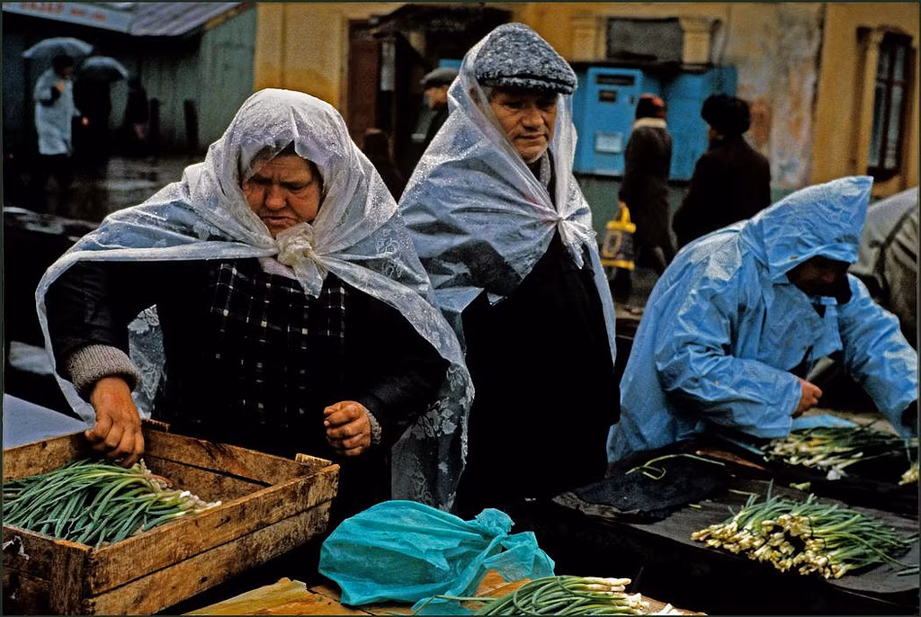 Những người phụ nữ sắp xếp hành củ ở chợ dưới cơn mưa. Ảnh: Ian Berry/Magnum Photos.