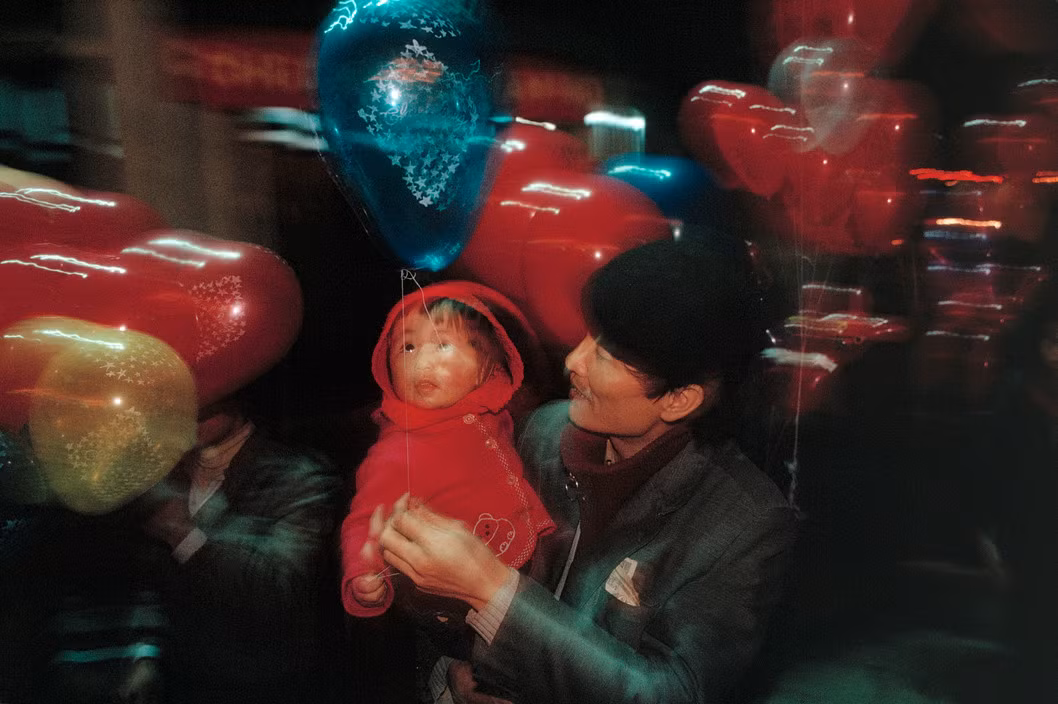 Em bé được bố mua bóng bay khi dạo chơi trên đường phố Hà Nội Tết 1989. Ảnh: David Alan Harvey/Magnum.