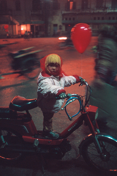 Em bé đứng trên chiếc xe Peugeot buộc quả bóng bay khi đi chơi Tết với bố. Ảnh: David Alan Harvey/Magnum.