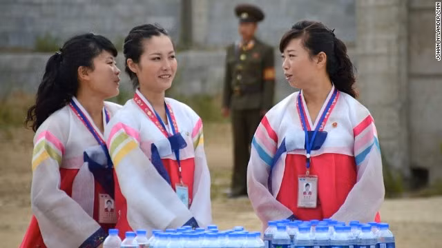 Các hướng dẫn viên của một hãng du lịch ở địa phương đứng trước bàn tiếp nước cho các tay đua trong cuộc đua xe đạp quốc tế.