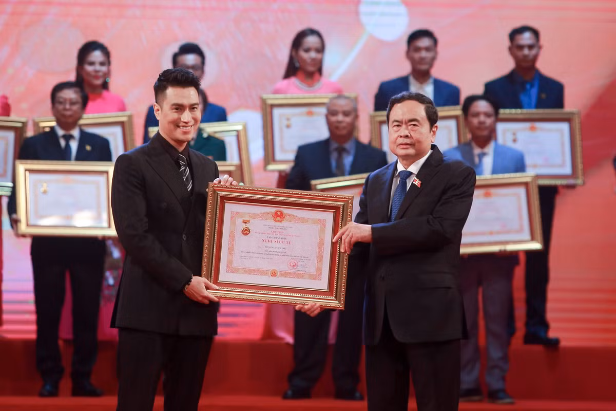 Diễn viên Việt Anh nở nụ cười rạng rỡ khi được nhận danh hiệu Nghệ sĩ Ưu tú từ tay Phó Chủ tịch Quốc hội Trần Thanh Mẫn.