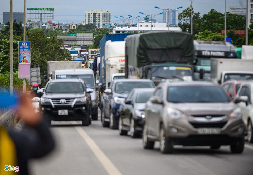 Các phương tiện chen chúc nhau trên đường dẫn lên cầu. Ôtô đi cả 3 làn khiến người đi xe máy phải luồn lách để vượt lên trên.