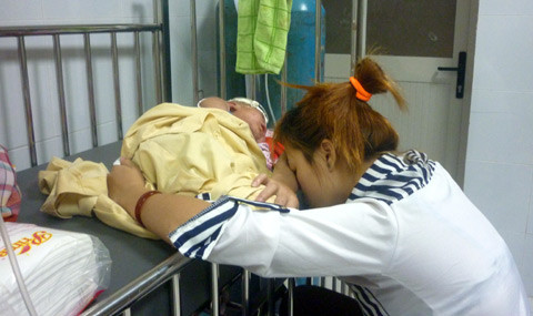 Người mẹ mệt mỏi thiếp đi bên cạnh giường bệnh của con. Cháu bé này đang bị phát ban nặng do mắc sởi. Ảnh: VNN