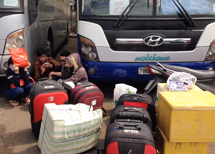 Một nhóm hành khách ngồi vật vã chờ xe khởi hành