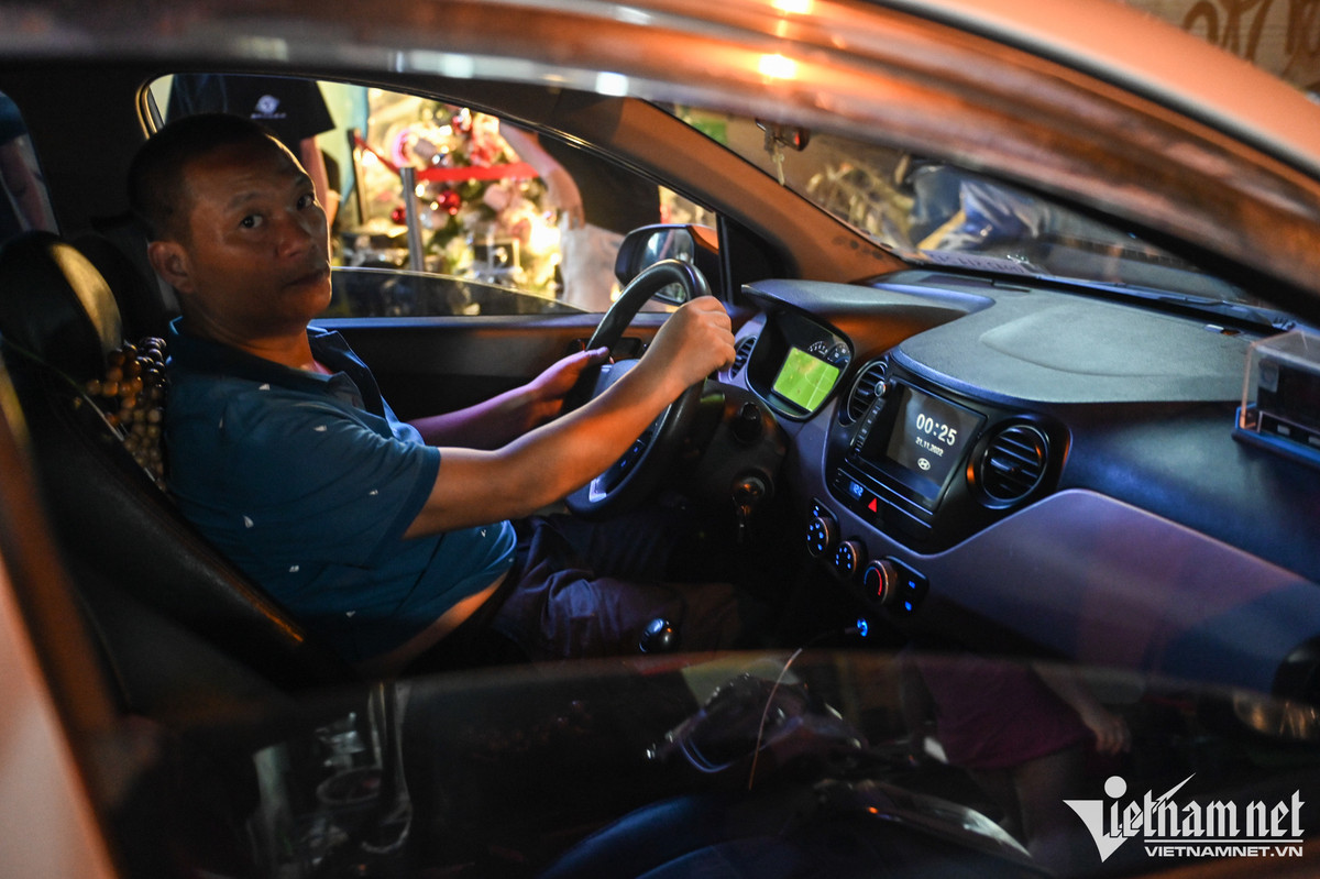 Một tài xế taxi tranh thủ theo dõi trận Qatar gặp Ecuador qua điện thoại khi đang trên đường di chuyển.