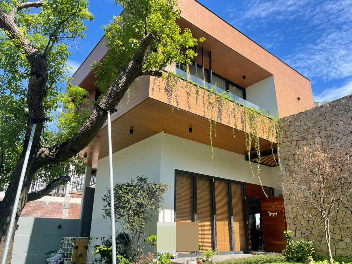 Khoảng đệm trước khi vào nhà với bức tường bằng đá mộc mạc, làm điểm nhấn trong khuôn viên vườn. Màu xanh đang dần bao bọc, phủ khắp nơi.