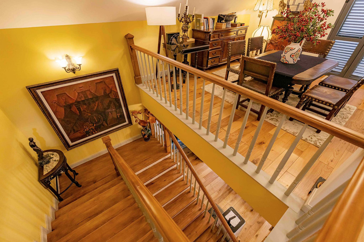 Lối lên tầng áp mái với cầu thang và lan can có tay vịn bằng gỗ, gợi nhớ mùa đông tuyết trắng châu Âu.