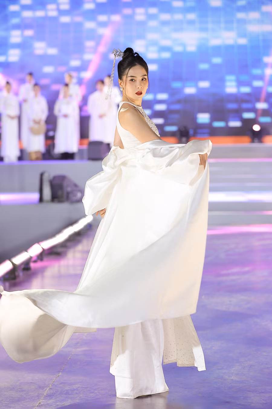 Với vị trí vedette, MC Mai Ngọc được giao mặc bộ áo dài cách điệu với phần vai trần và những hạt ngọc trai đính kết tinh tế. Ngoài ra, thiết kế còn có thêm áo choàng và chiếc trâm cài tóc tạo khiến Mai Ngọc lộng lẫy và đài các. Cô nhận được nhiều tràng vỗ tay cổ vũ với phong cách diễn cuốn hút khi đã lâu mới trở lại trình diễn thời trang