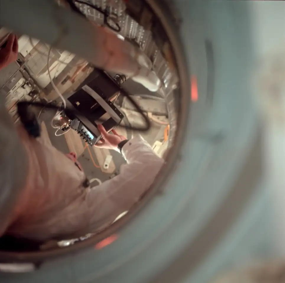 Hình ảnh cho thấy Neil Armstrong ở đường hấm nối giữa khoang Mặt Trăng (Lunar Module) và khoang chỉ huy. Trước mặt ông là màn hình TV kết nối với camera. Markus Mehring, cây viết của Apollo Journal cho biết vào thời điểm đó, các phi hành gia rất khó khăn trong việc canh góc camera sao cho đẹp. Do đó, họ được cấp một chiếc TV để nhìn rõ khung hình từ ống kính.