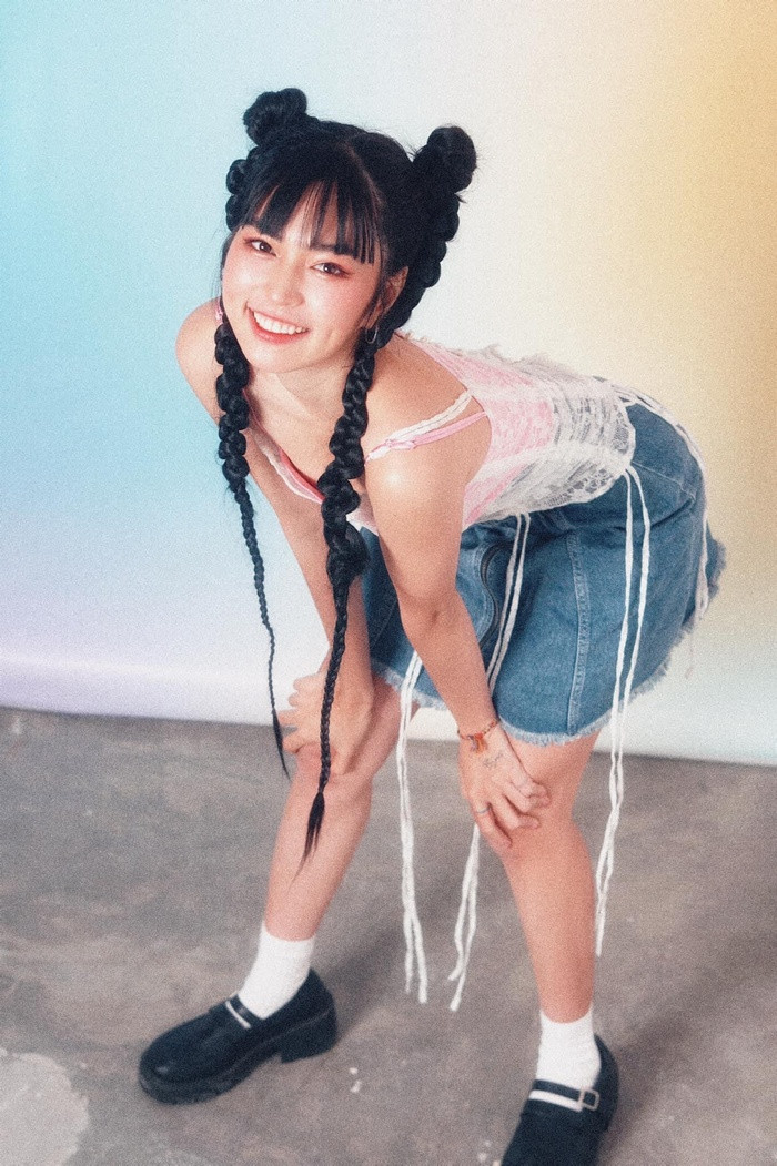 Nữ diễn viên chọn set đồ đậm chất phong cách Y2K với chiếc váy jean đặc trưng và áo hai nữ tính nhưng không kém phần cá tính. Điểm nhấn chính là mái tóc được búi cao hai bên và tết dài qua hông. Kết hợp cùng mái ngố xì-tin, Khánh Vân không khác gì một cô nữ sinh của những năm cuối thập niên 90.