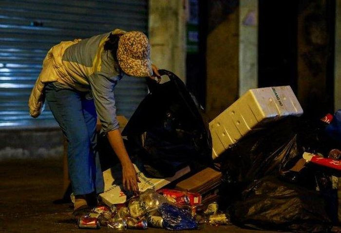 Chị Lan đã làm công việc này được 28 năm, một buổi làm việc của chị bắt đầu từ 17 giờ cho đến 2 giờ sáng hôm sau. "Những mùa khác còn đỡ, chứ mùa Đông cực lắm, bởi thời điểm làm việc chính là lúc nhiệt độ xuống thấp nhất trong ngày. Hôm nào cũng mong xong việc thật sớm để về với mái ấm gia đình, vùi mình vào chăn nằm ngủ", chị Lan nói. (Chị Lan tranh thủ thu nhặt thêm chai nhựa để bán đồ phế thải, kiếm thêm thu nhập)
