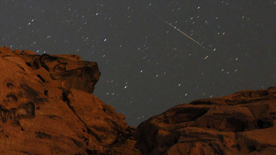 Vệt sao băng Perseid màu hồng và xanh lục trên một sa thạch nhô lên tại khu vực hồ Mead ở Nevada, Mỹ ngày 8.8.2021. Ảnh: AFP/Getty