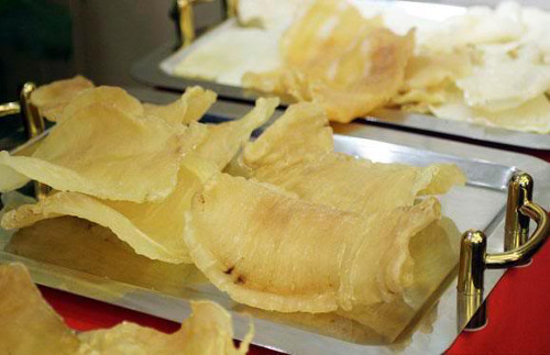 Cho bóng cá vào rán vàng giòn, vớt ra để ráo dầu. Phi thơm tỏi với ít dầu ăn rồi cho lạp xưởng vào rán chín, thêm hạt điều, ớt, hạt nêm, nêm vừa ăn. Cuối cùng, cho bóng cá, hành lá vào đảo nhanh, tắt lửa.