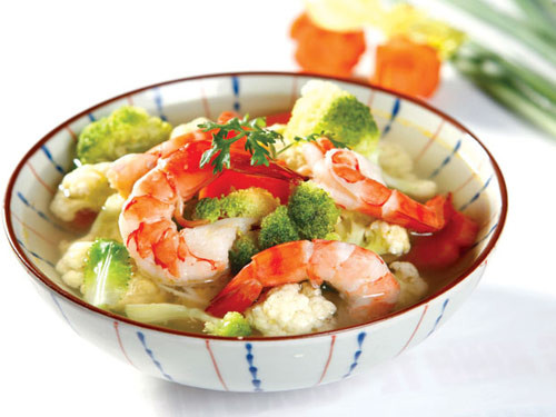 Trải 1 lớp bóng cá ra khay, phết vào 1 lớp giò mỏng, đặt lên 1 lớp bóng cá, 1 miếng trứng chiên, sau cùng đặt lớp bóng cá lên, cuộn tròn lại, đem hấp chín, cắt lát vừa ăn. Nấu sôi 500ml nước sạch, cho tôm vào nấu sôi bùng, hạ lửa, vớt bọt, cho bóng cá, bông cải, cà rốt vào, nấu khoảng 4 phút, nêm muối, hạt nêm cho vừa ăn.