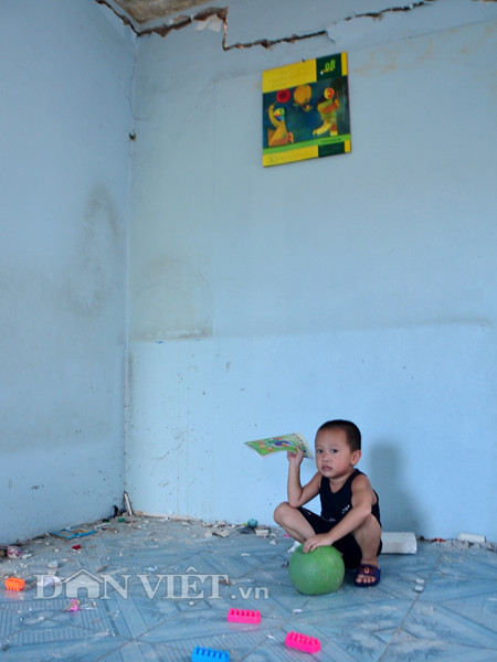 Một bé trai cố nhao vào trong nhà nhặt đồ chơi còn sót lại trong ngôi nhà của mình.